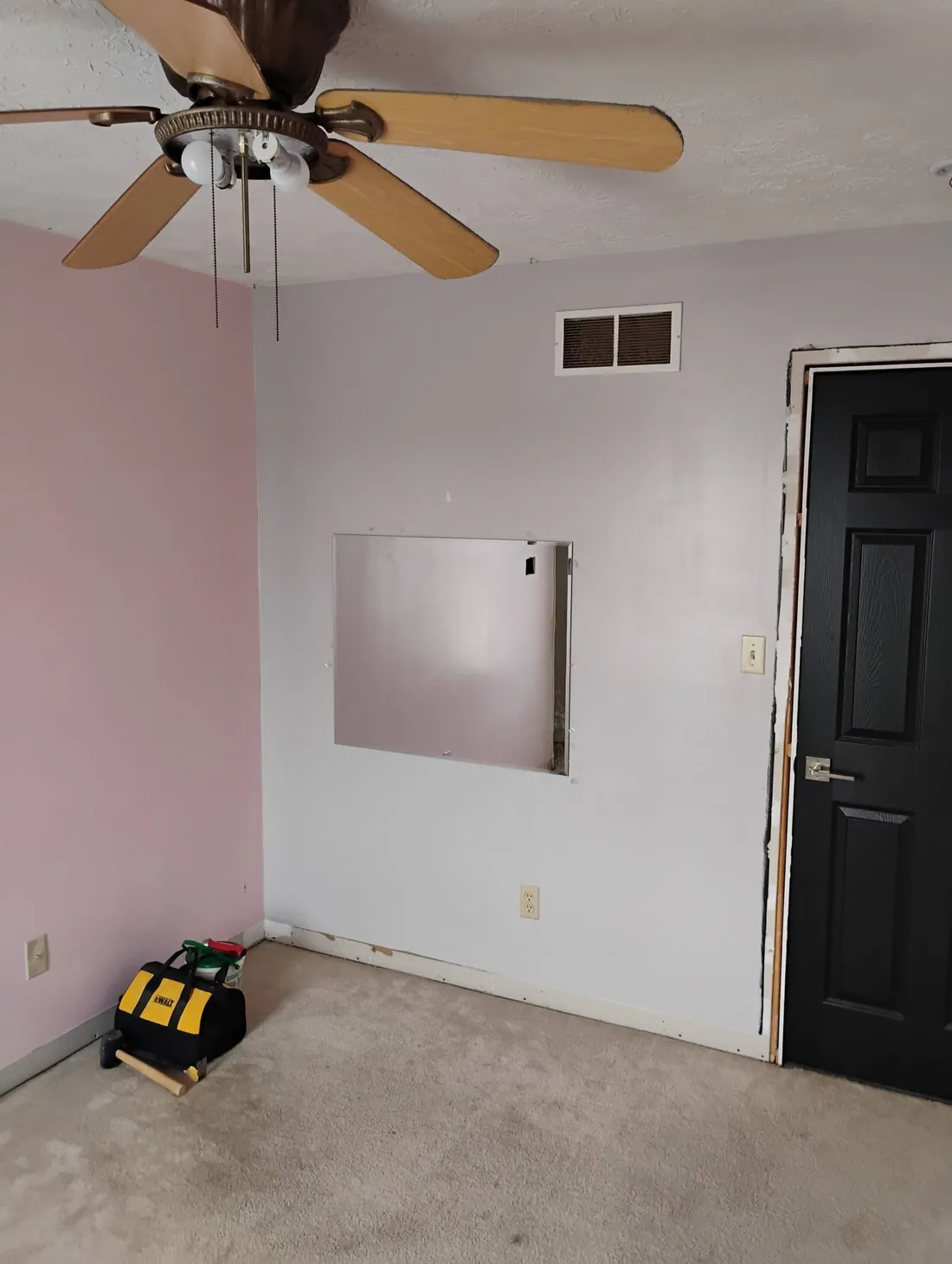 Bedroom before painting with pink walls, dated trim and a dark door